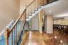 Two-story entryway featuring a wood staircase with blue carpeted treads, mirrored wall accents, and wood-finish flooring