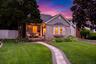 Stone and siding exterior featuring a front porch, bay window, paver walkway, and a manicured lawn