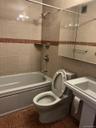 Bathroom featuring tiled shower / bath combo, toilet, and tile walls