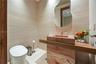 Designer powder room with full-height travertine wall tiles, carved red-veined stone vessel sink on matching stone vanity base, sculptural freeform mi