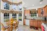 Kitchen featuring white appliances, brown cabinetry, glass insert cabinets, backsplash, and recessed lighting