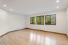 Spacious room featuring light wood-finish flooring, recessed ceiling lighting, and multiple windows providing ample natural light