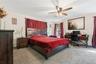 Spacious room featuring neutral carpeting, a ceiling fan with light fixture, and natural light from a double window
