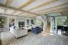 Living room featuring beamed ceiling, a lit fireplace, and stairway