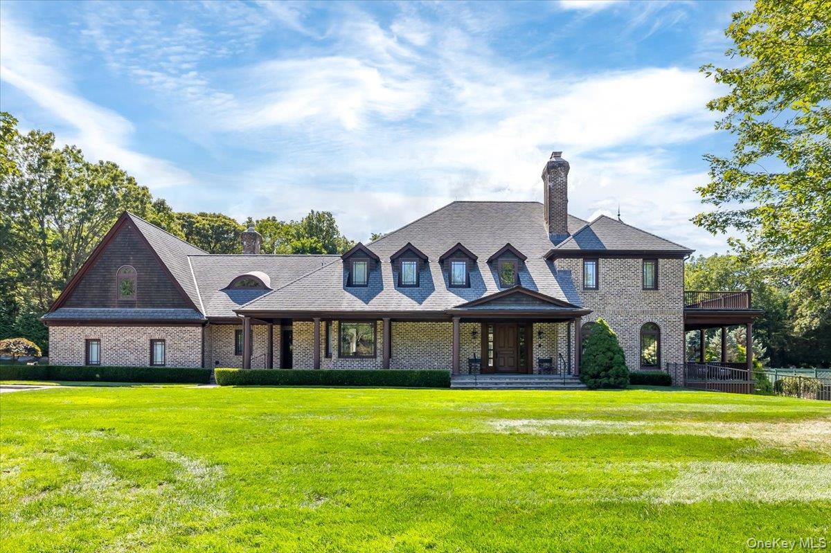 View of front of property featuring a chimney, a front lawn, and brick siding