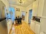 Kitchen with stainless steel appliances, white cabinets, light wood finished floors, and light countertops