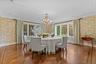 Elegant formal dining room featuring a stunning crystal chandelier, patterned wallpaper, and beautiful herringbone hardwood floors. Expansive windows