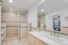 Ensuite bathroom featuring vanity, a stall shower, tile walls, light tile patterned floors, and recessed lighting