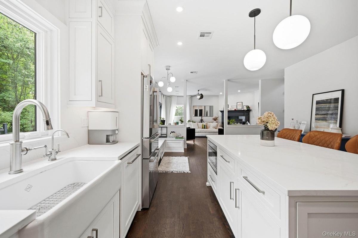 Gourmet kitchen featuring a farmhouse sink with built in food disposal, and a spacious island with Carrera gold Silestone countertops and pendant ligh