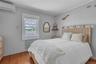 Bedroom featuring a wall mounted AC, crown molding, wood finished floors, and radiator