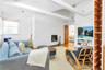 Living room with brick wall, beam ceiling, a brick fireplace, and light hardwood / wood-style flooring