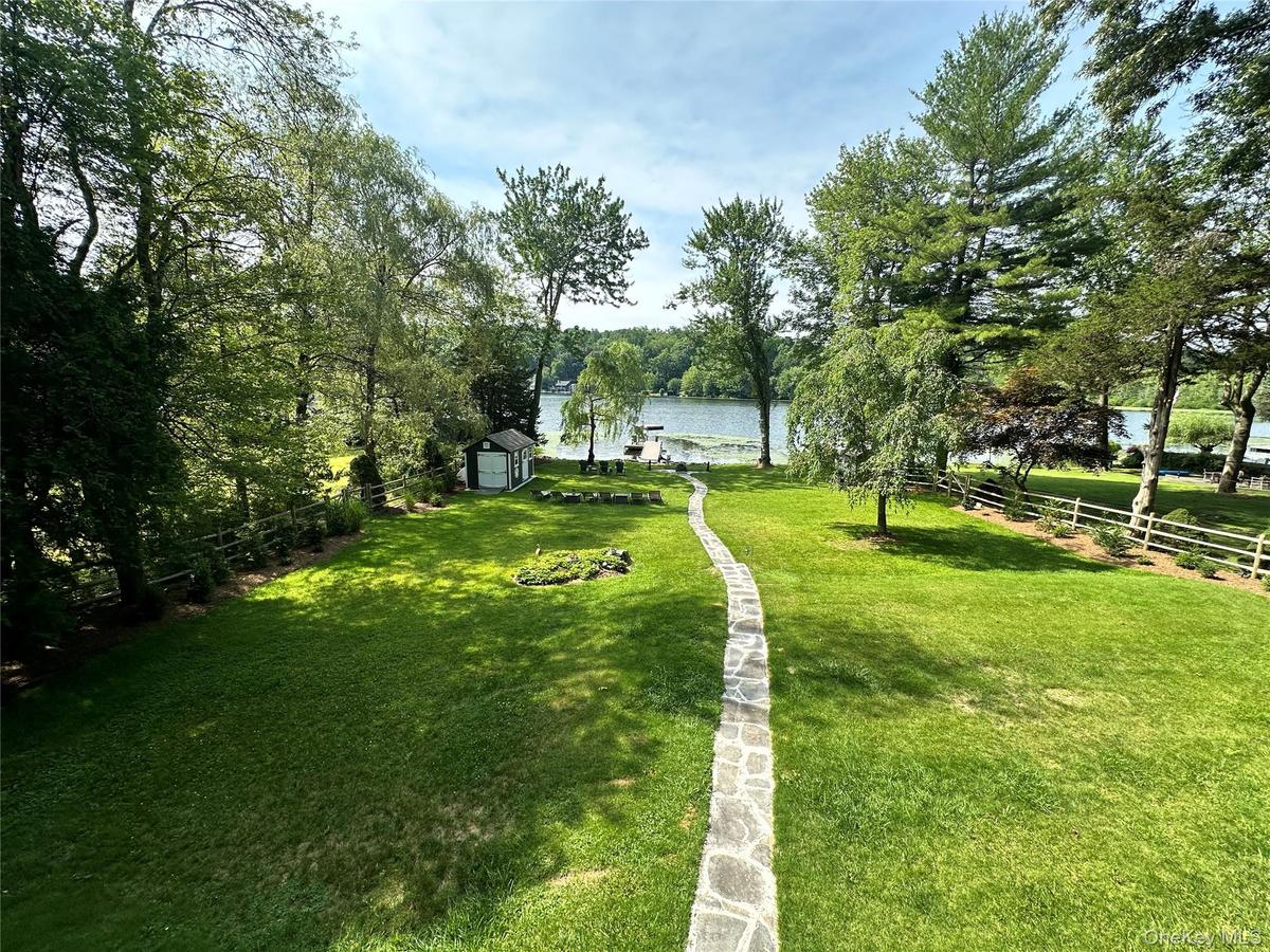 View of home's community featuring a fenced backyard, a water view, and a shed