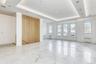 Empty room with a tray ceiling, light marble finish flooring, and radiator heating unit