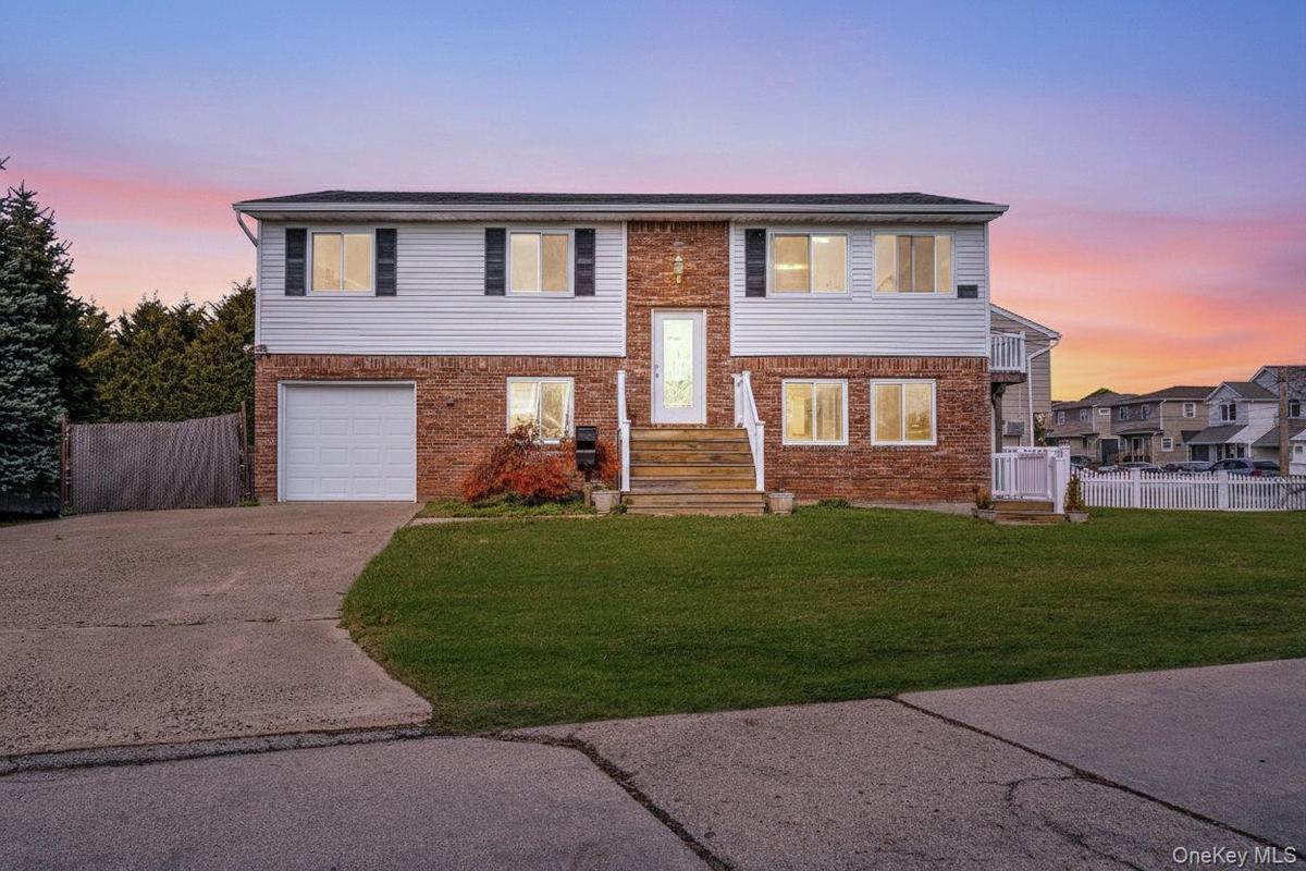 Split foyer home featuring concrete driveway, brick siding, and a garage