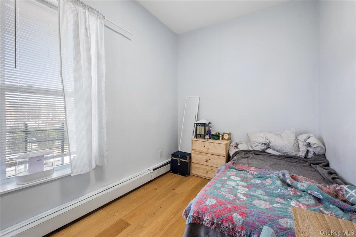 1st Floor Apartment bedroom features hardwood floors and a window with blinds, providing natural light