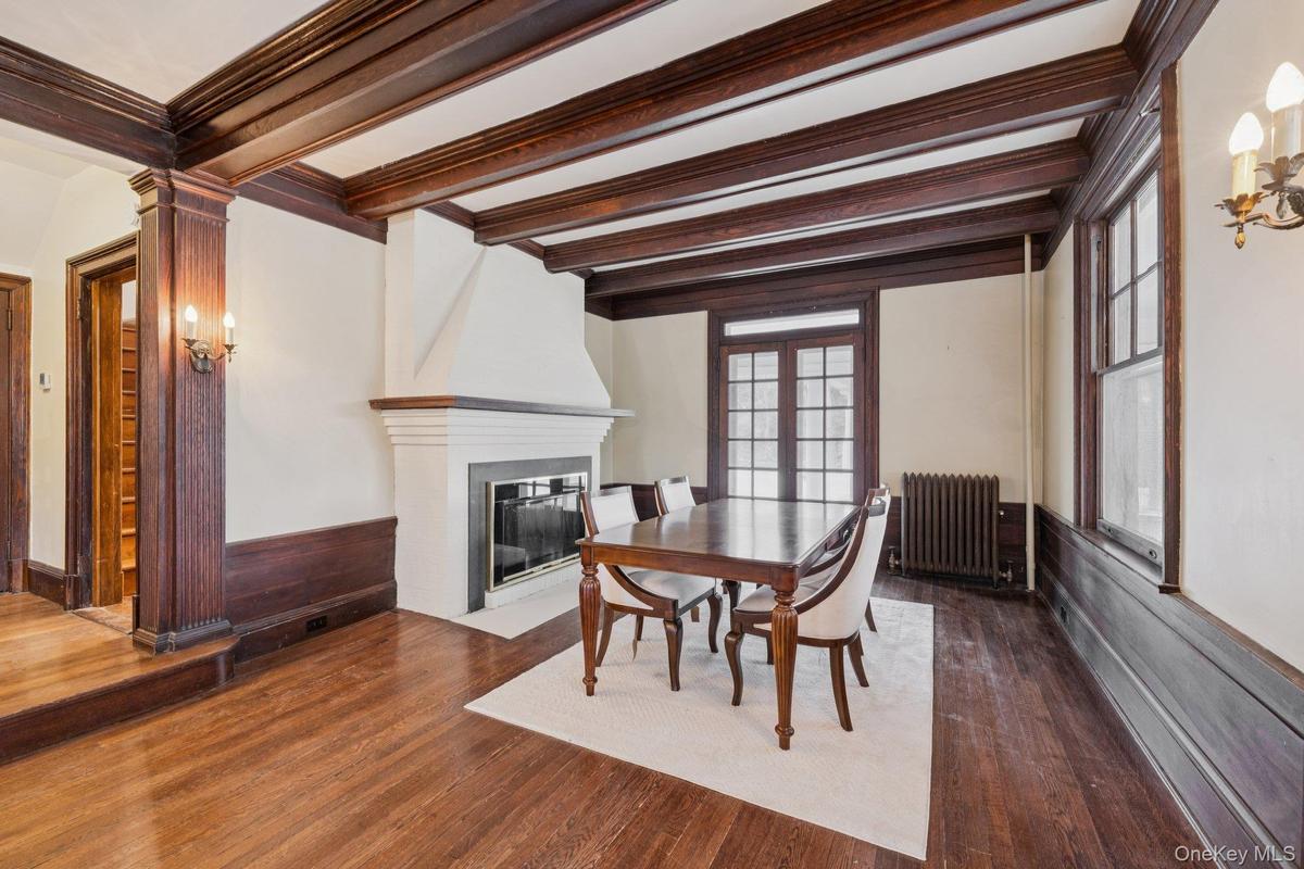 Dining area featuring radiator, dark wood finished floors, a fireplace, french doors, and ornamental molding