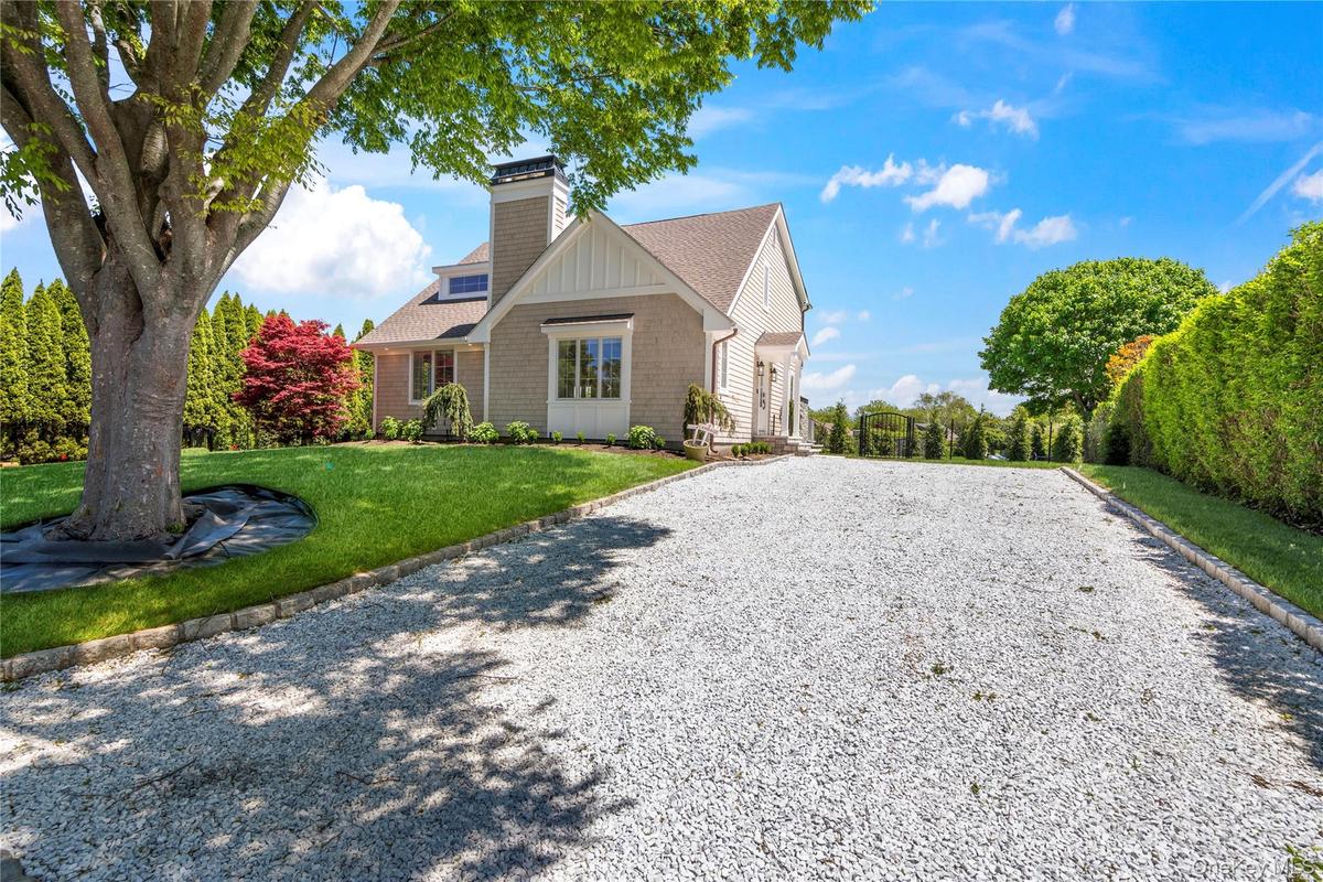 View of front of property featuring a front lawn, driveway, roof with shingles, and a chimney