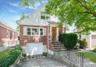Bungalow with brick siding, concrete driveway, an attached garage, and a gate
