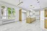 Kitchen featuring white cabinets, radiator, an island with sink, decorative light fixtures, and recessed lighting