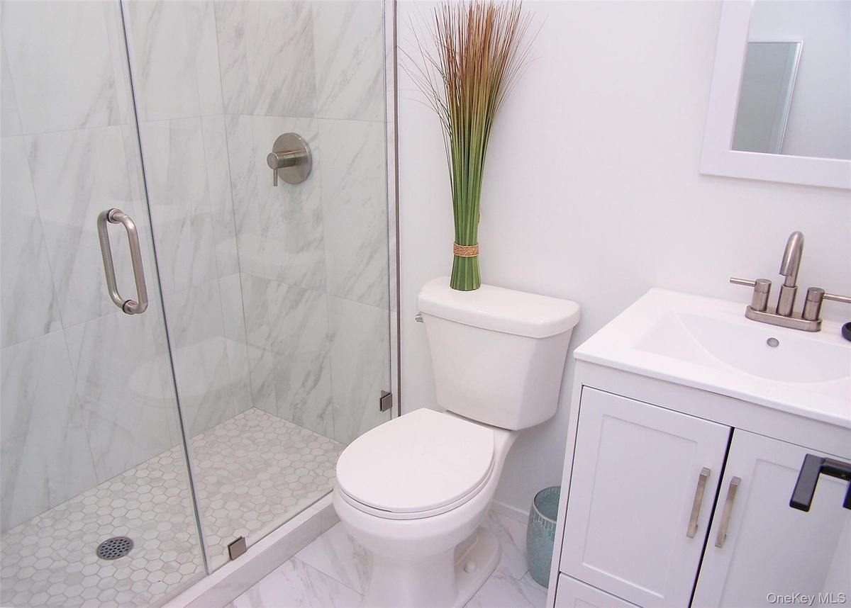 Bathroom featuring a marble finish shower, vanity, and marble look tile flooring