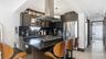 Kitchen with ornamental molding, a kitchen breakfast bar, island range hood, decorative backsplash, and dark stone countertops