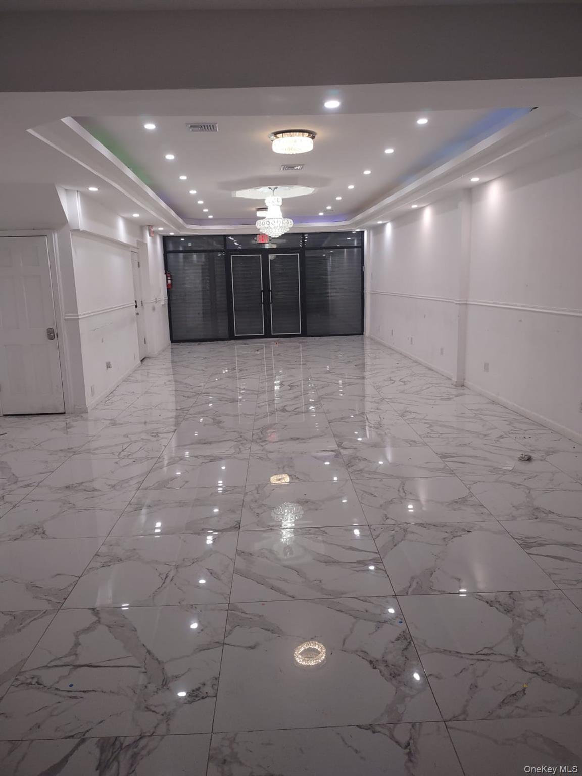 Spare room with a raised ceiling, light marble finish flooring, and recessed lighting