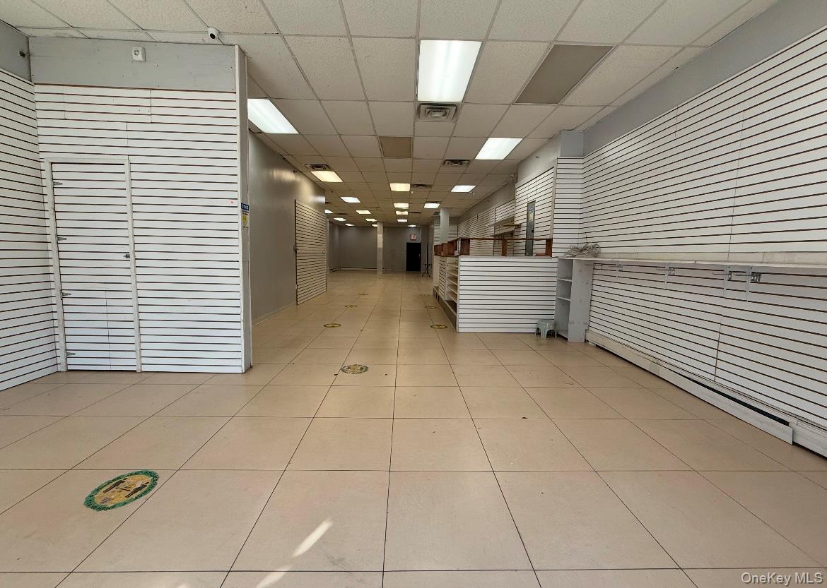 Hall with a drop ceiling and light tile patterned floors