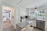 Kitchen featuring dishwasher, light wood finished floors, decorative light fixtures, white cabinetry, and ornamental molding