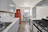 Contemporary kitchen featuring light gray cabinetry, coordinating countertops, a stainless steel sink, and wood-finish flooring