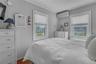 Bedroom with a wall unit AC and wood finished floors