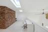 Unfurnished office featuring ceiling fan, light wood-type flooring, and brick wall