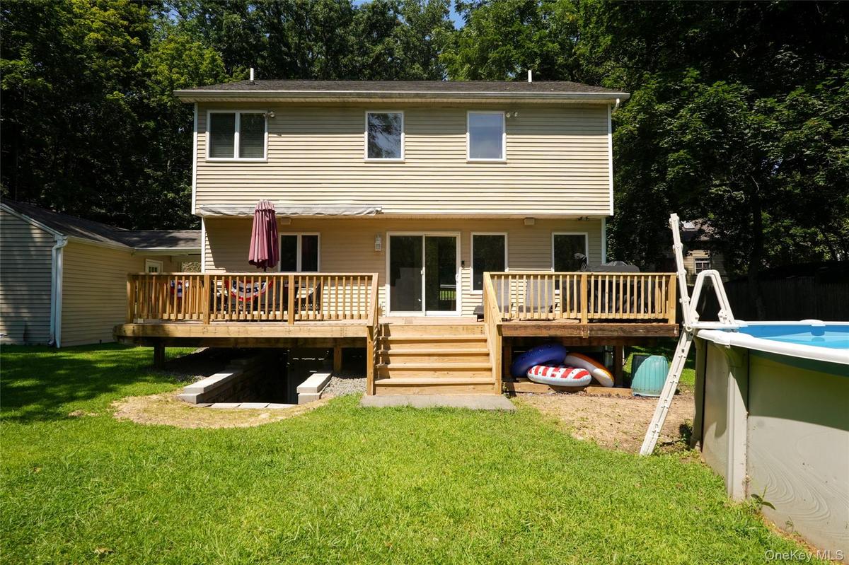 Part of the backyard, new deck with retractable awning, and above-ground swimming pool.