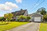 Cape cod home featuring a garage, driveway, a chimney, and a shingled roof