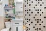 Bathroom featuring a white vanity with paneling and dark hardware, a stone-finish countertop, and a chrome-finish faucet