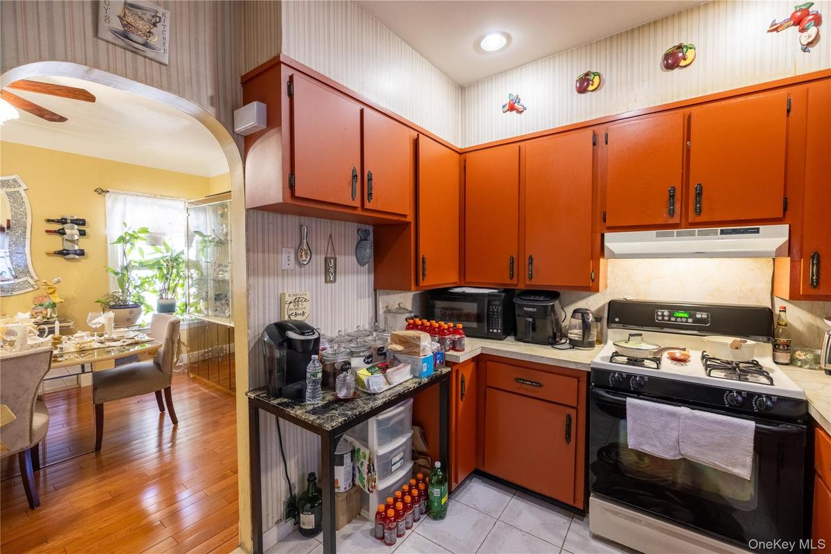 Kitchen featuring range with gas stovetop, light countertops, arched walkways, black microwave, and wallpapered walls
