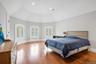 Bedroom with lofted ceiling, multiple windows, and wood finished floors