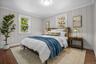 Bright secondary bedroom with hardwood floors, crown molding, and double windows overlooking the landscaped yard.