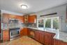 Kitchen featuring stainless steel appliances, light stone countertops, glass insert cabinets, and wood finish cabinetry
