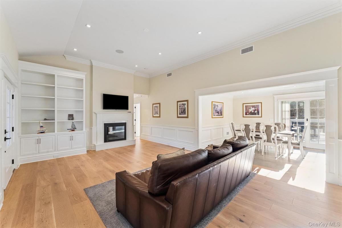 Living room with a wainscoted walls, light wood flooring, and a glass covered fireplace.