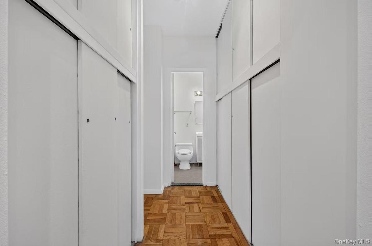Hallway featuring wood-finish parquet flooring and white sliding closet doors