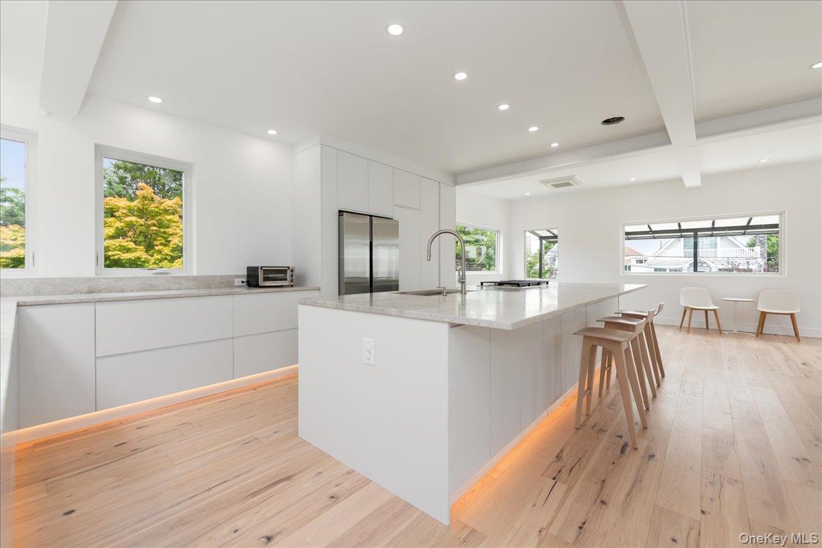 Kitchen featuring modern cabinets, recessed lighting, light wood-style floors, white cabinetry, and beam ceiling