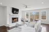 Living room with ceiling fan, baseboards, wood finished floors, and a warm lit fireplace