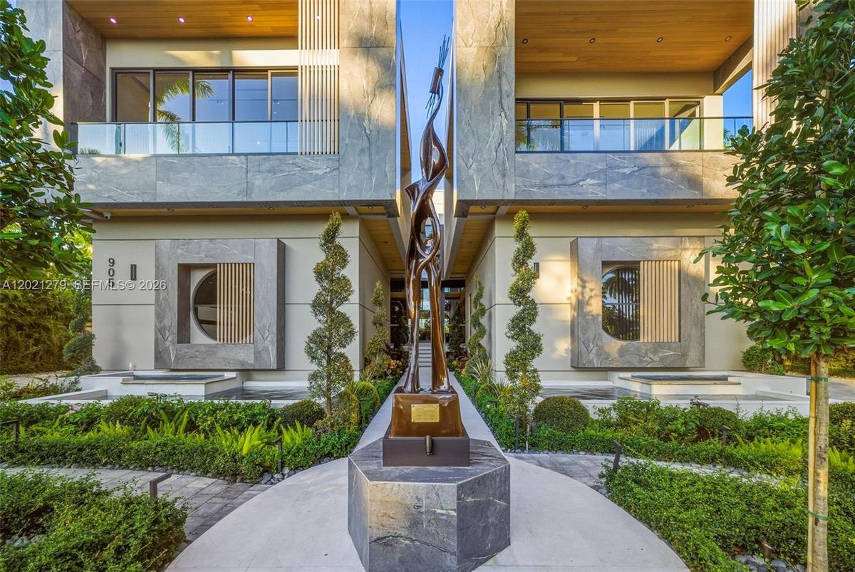 Close-up of paver entry walkway centered on large-scale bronze figurative sculpture on stone pedestal, flanked by spiral topiaries, reflecting pools,