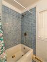 Bathroom featuring crown molding, baseboard heating, and shower / tub combo