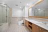 Bathroom with double vanity, a wainscoted wall, tile walls, a stall shower, and recessed lighting