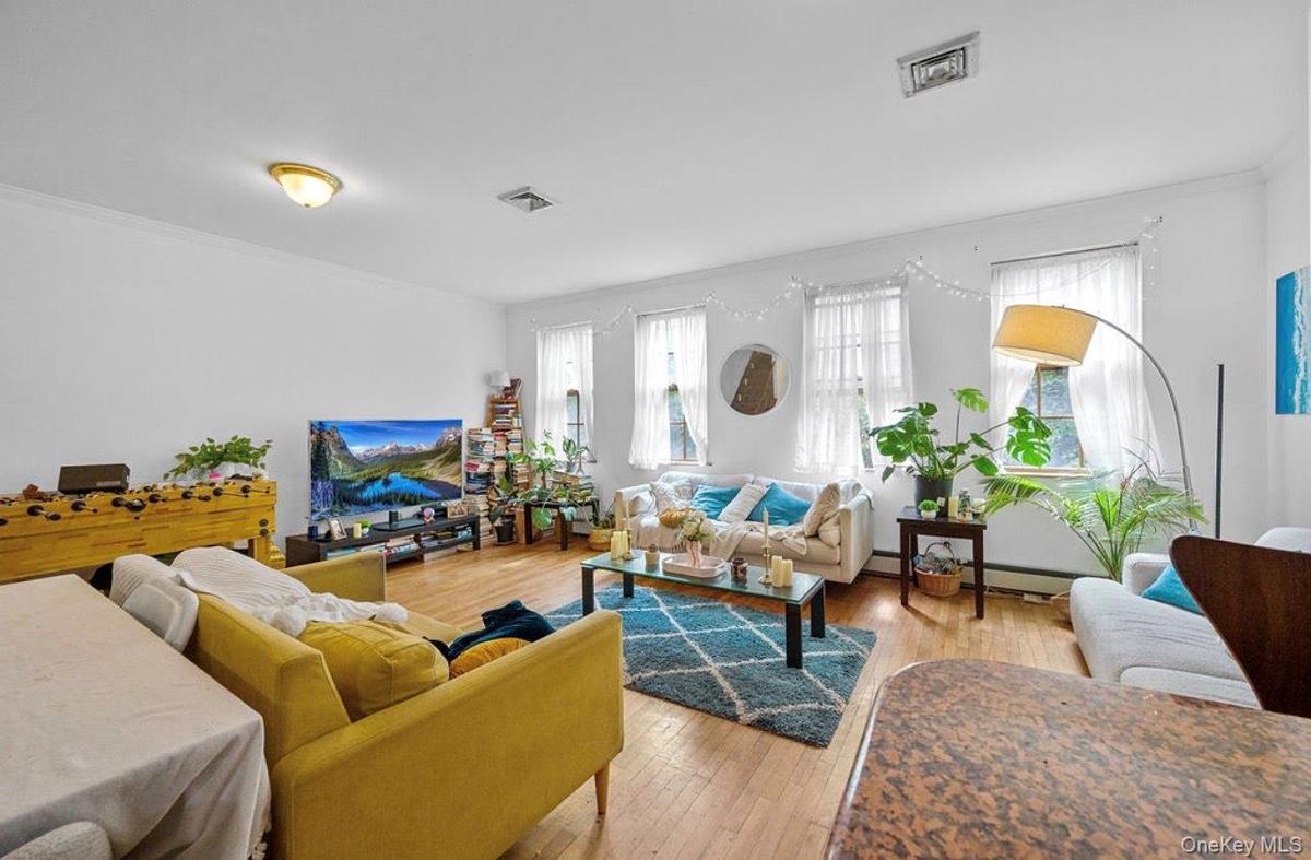 Living room featuring light wood-style floors, crown molding, and baseboard heating