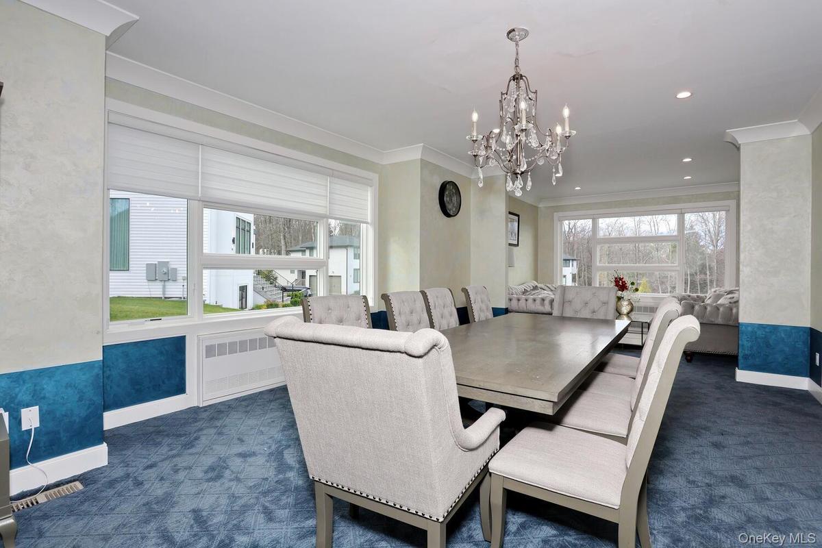 Dining room featuring radiator heating unit, dark colored carpet, ornamental molding, and a chandelier