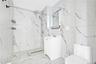 Full bathroom featuring a marble finish shower, vanity, light marble finish flooring, stone wall, and tile walls