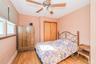 Room featuring wood-finish flooring, a ceiling fan with integrated lighting, and a window with blinds