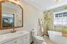 Bathroom featuring a freestanding bath, crown molding, vanity, a baseboard radiator, and light tile patterned flooring